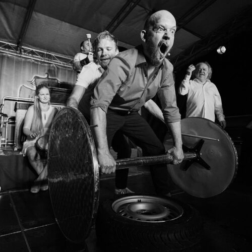 Schwarz-weiß Fotokunstwerk von 5 Personen. Ein Mann versucht ein Gewicht hochzuheben.