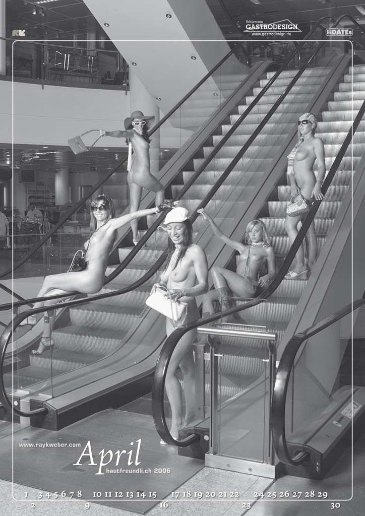 Es ist ein Kalenderblatt. 5 nackte Frauen sind auf einer Rollletreppe eines Einkaufzentrum.
