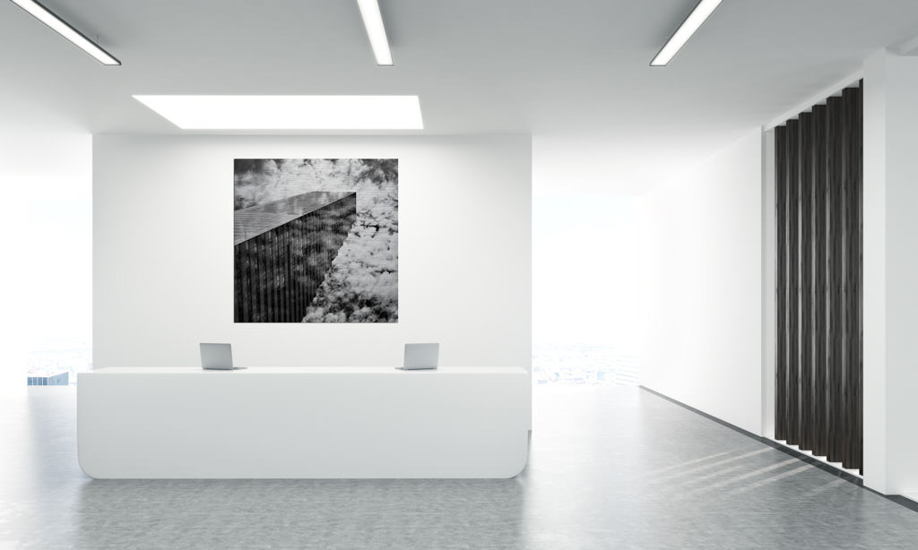 Ein schwarz-weiße Fotokunstwerk hängt in einem Büro. Es bildet einen Wolkenkratzer in der Schweiz ab.